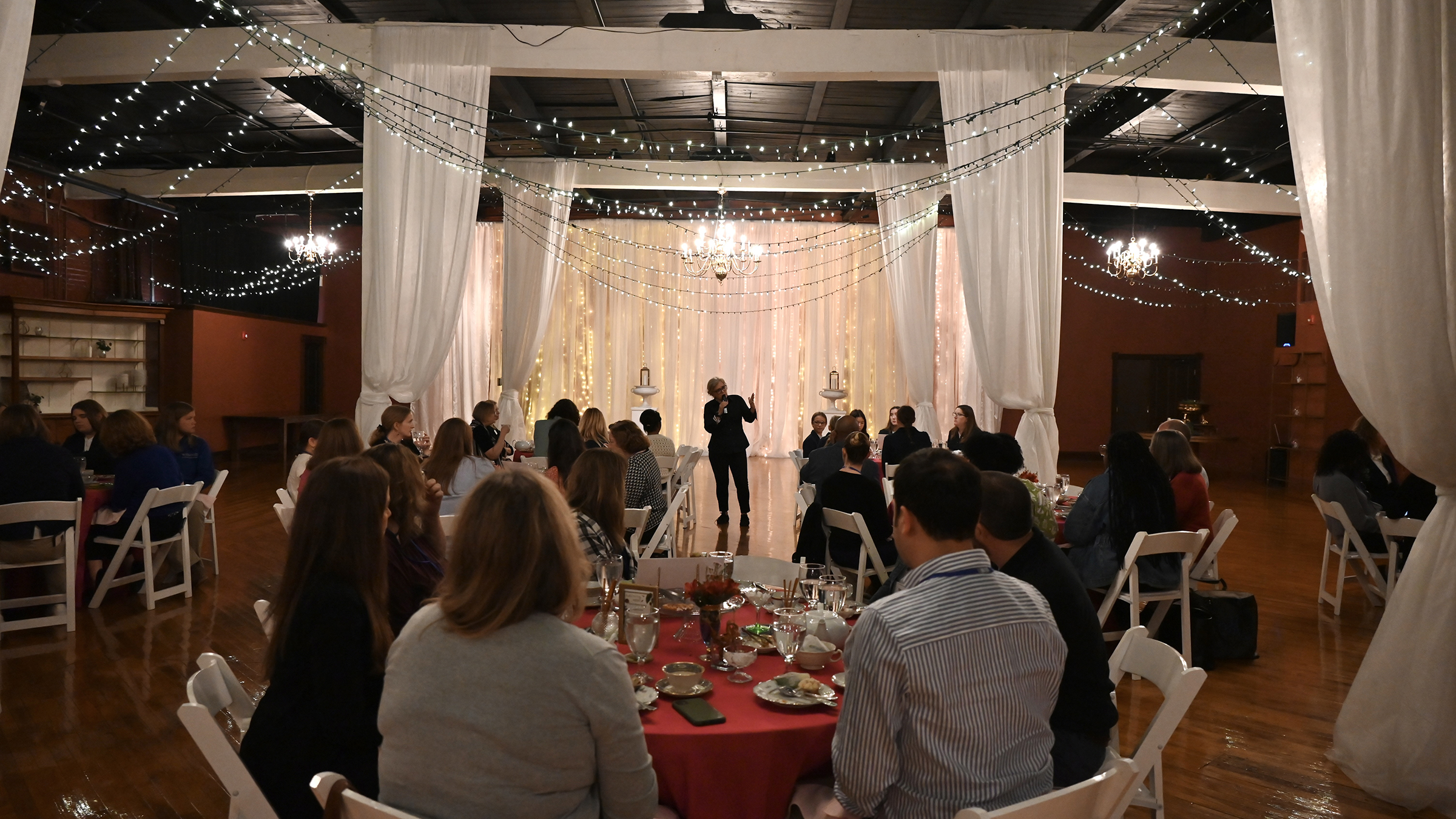 People sit at tables while someone speaks