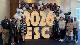 A group of attendees from UK around a 2026 ESC display.