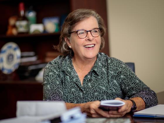 Nancy Cox at her desk, smiling