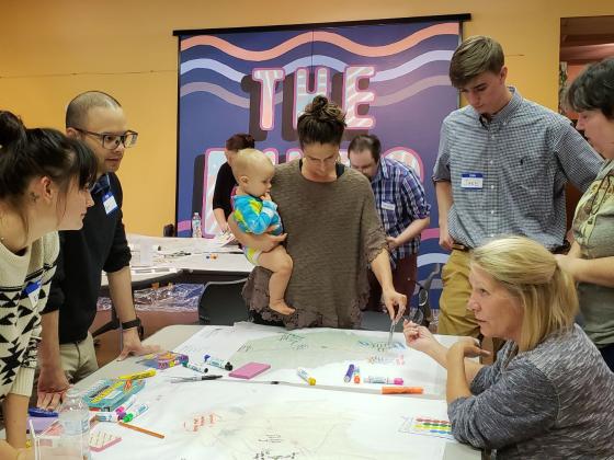 People lean over a table discussing landscape plans